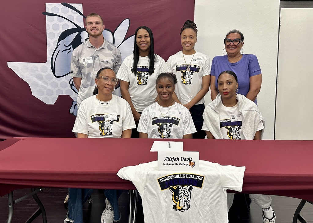 Teen girl seated behind table surrounded by family members.