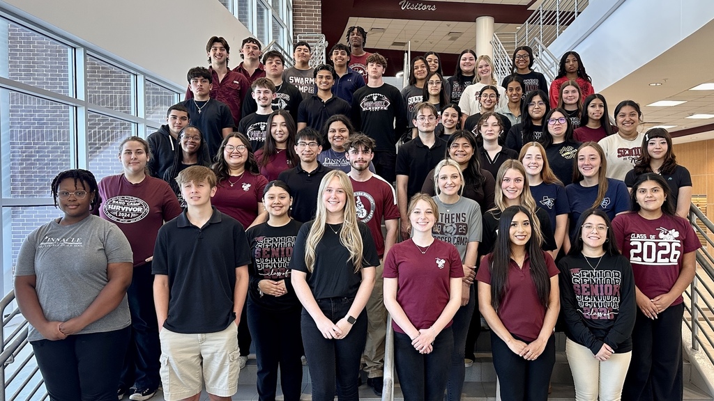 A large group of Athens High School students pose on the staircase inside the high school for a group photo celebrating students who have earned associate degrees through the PINNACLE Early College High School and dual-credit programs. Students are dressed in maroon, black and school spirit apparel inside the school’s main entryway.