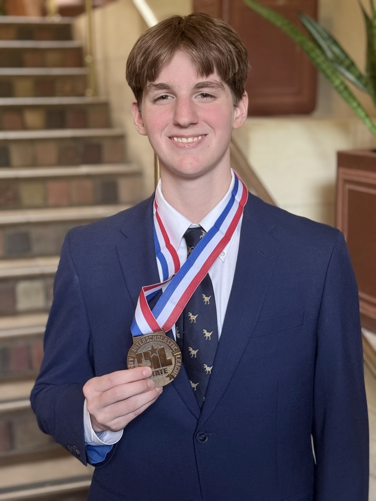 Photo of a young man in a blue suit holding a bronze medal