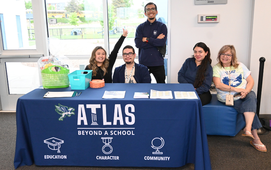 Staff smile at table with atlas on it