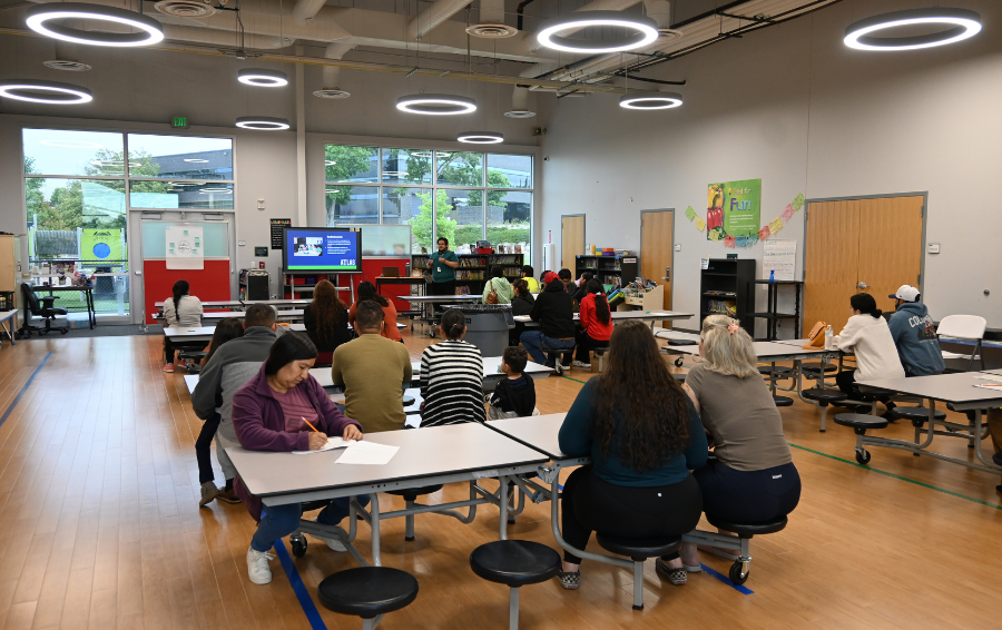 families sitting in cafeteria listening to presentation