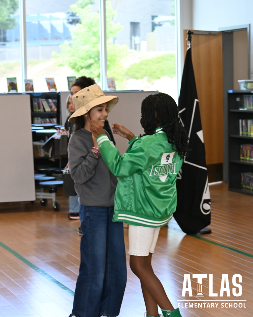 student puts hat on another student