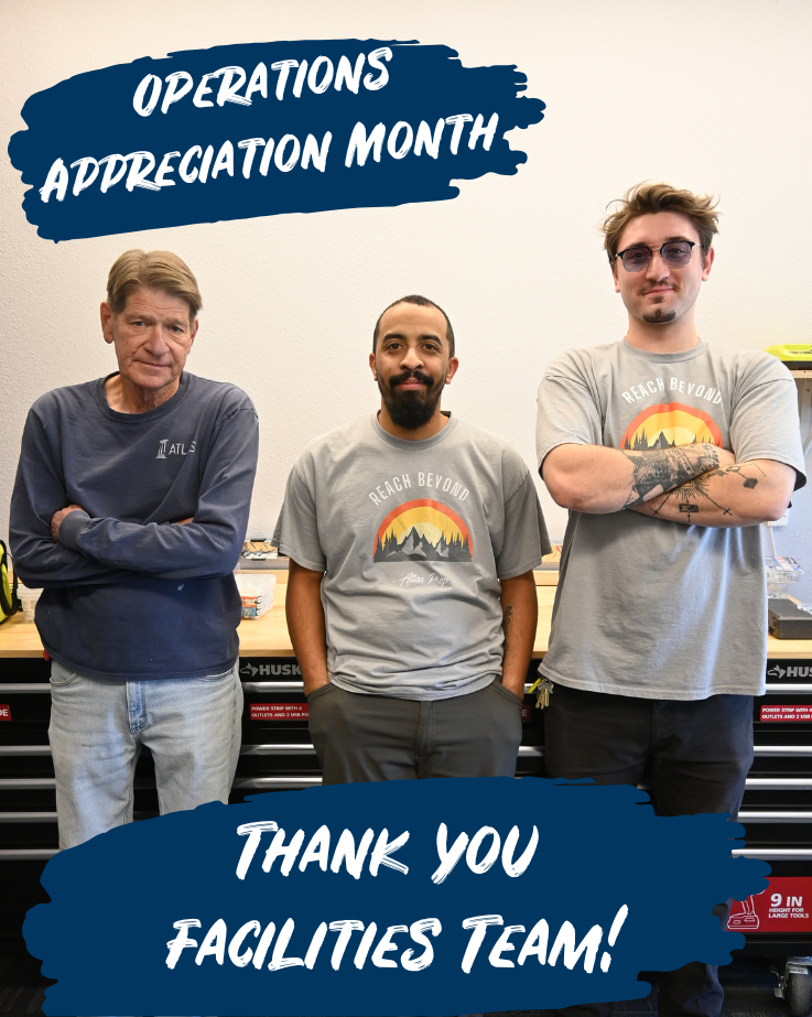 three men stand and two smile in front of a tool bench