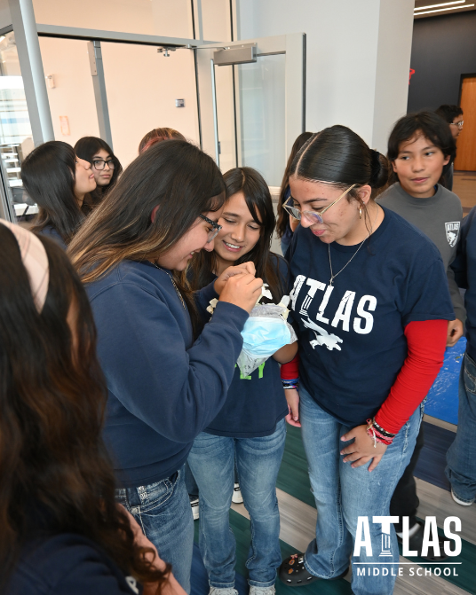 students smile in hallway while looking at their egg