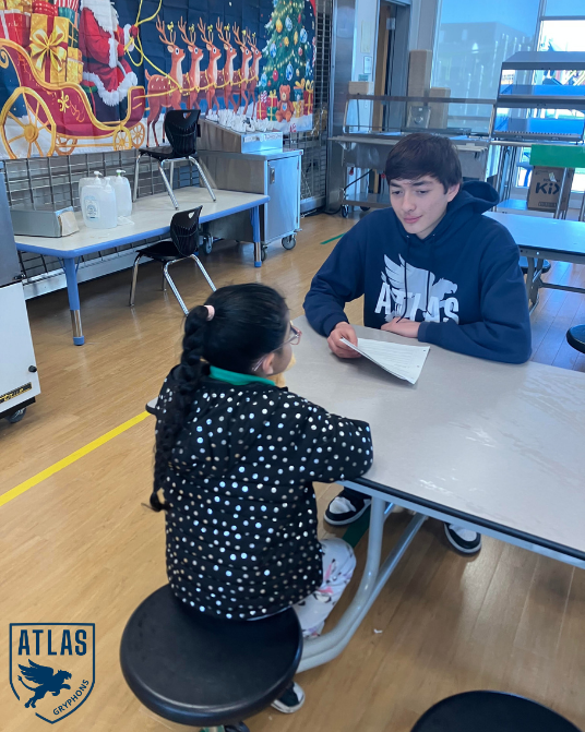 a high school student talks with an elementary student