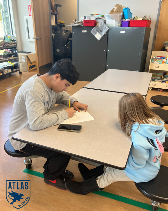 a high school student talks with an elementary student