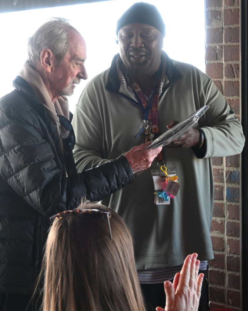 two men smile with a plaque