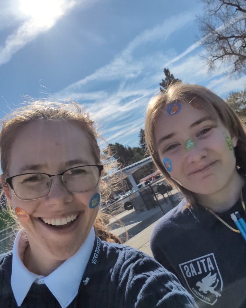 student and teacher smile with stickers on their faces