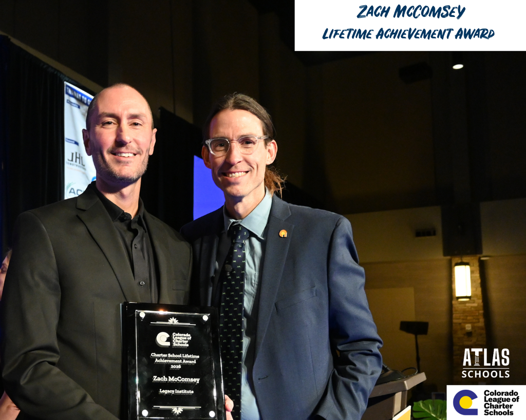 Two men stand, one with award