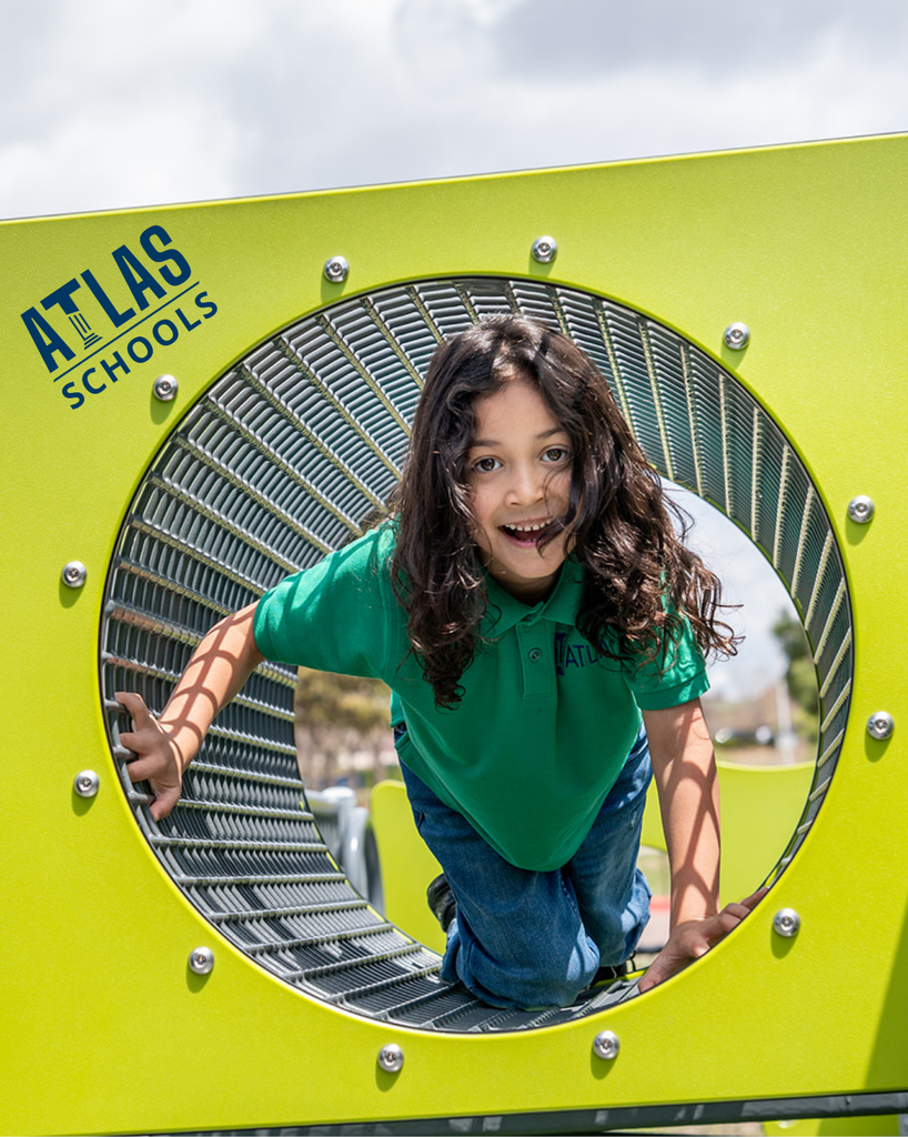student smiles while going through a tunnel on a playground