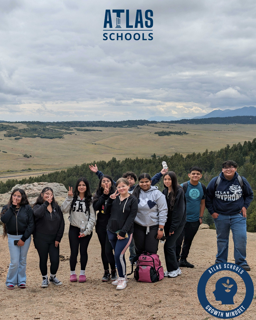 students smile at the top of a mountain