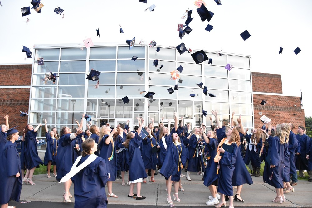 Members of Attica's Class of 2025 throw their graduation caps in the air.