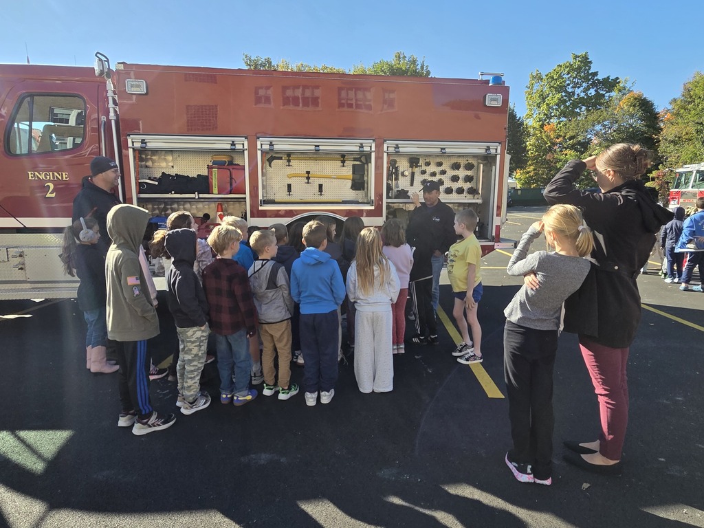 Firefighters teaching students about things they carry in their firetruck and what they use it for
