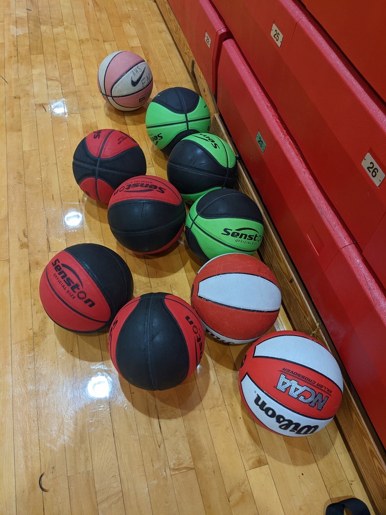 Colorful basketballs on the shiny wooden floor of the gym.