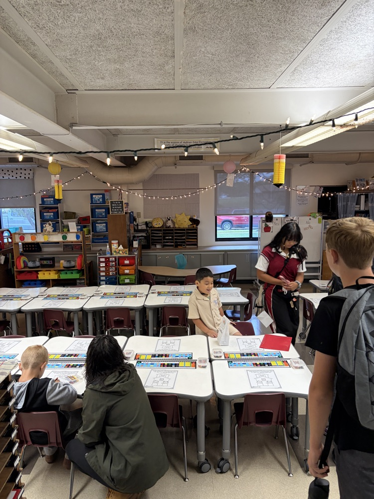 kindergarteners being dropped off by their parents in the classroom