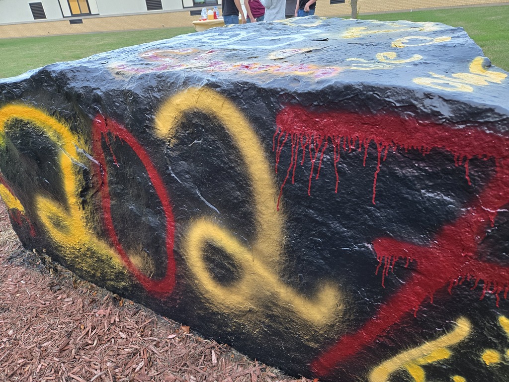 A large rock covered in colorful graffiti, showcasing various artistic designs and messages
