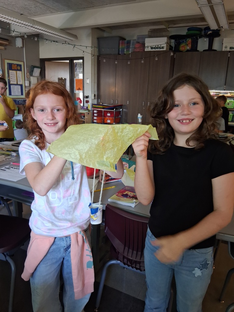 Students posing with their parachute designed to save Fred the gummy worm.