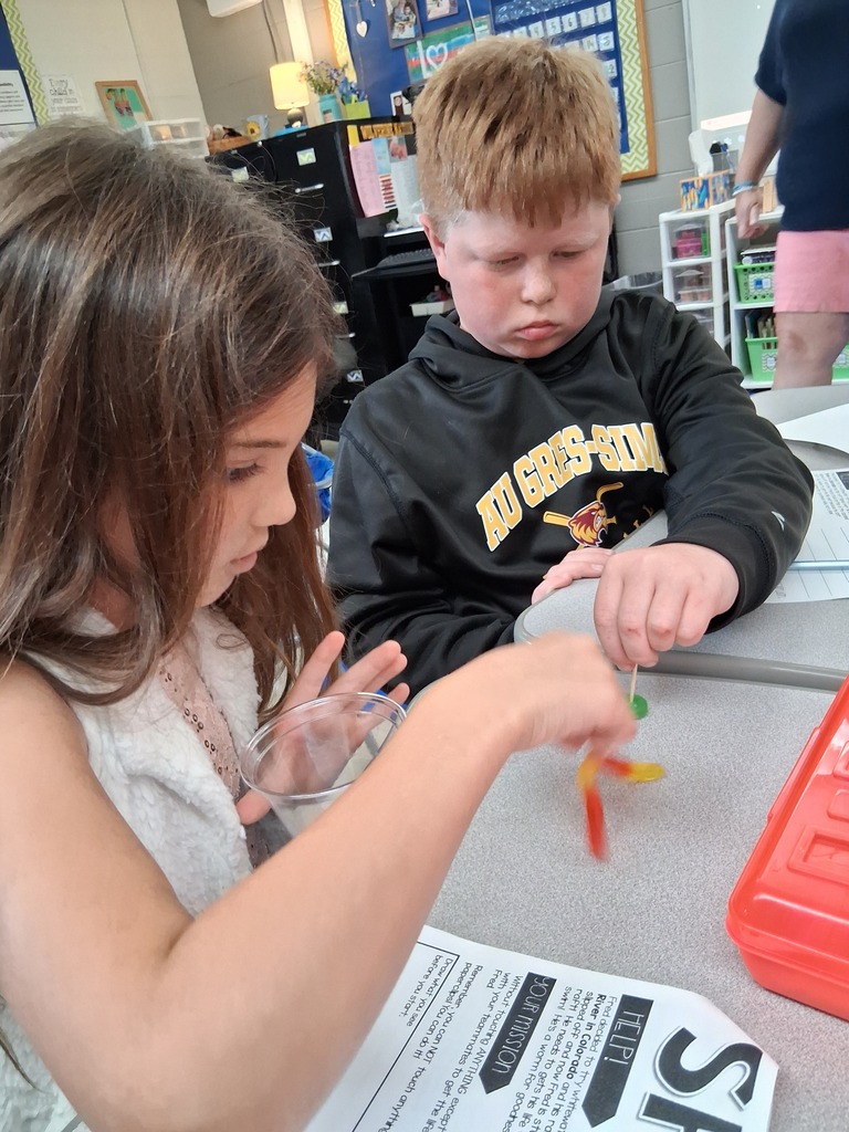 Students working together to put Fred the gummy worm through his life jacket gummy lifesaver.