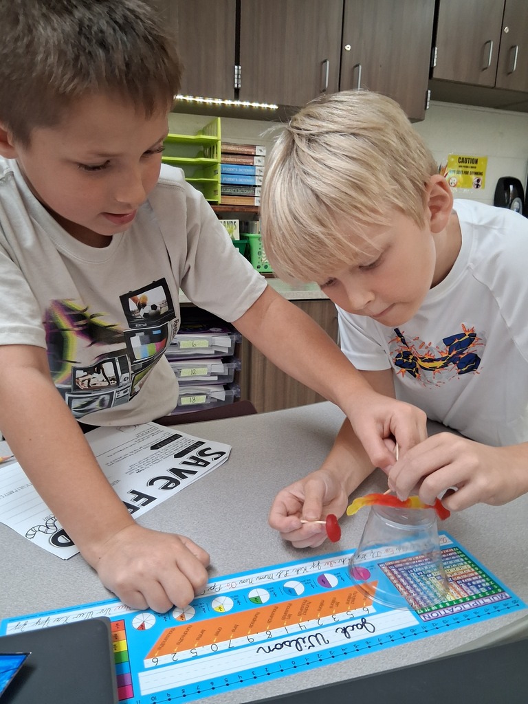 Students working together to put Fred the gummy worm through his life jacket gummy lifesaver.