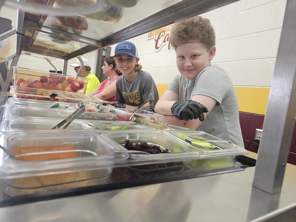 5th grade students participate in lunch duty and help serve younger students fruits vegetables.