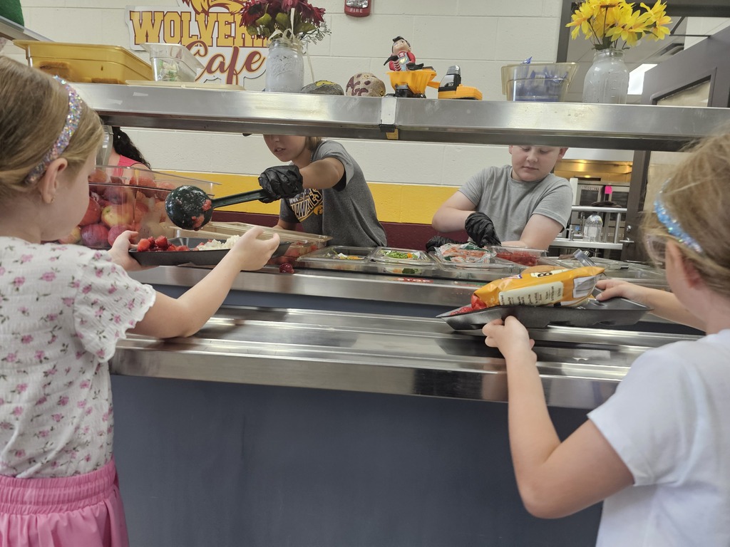 5th grade students participate in lunch duty and help serve younger students fruits vegetables.