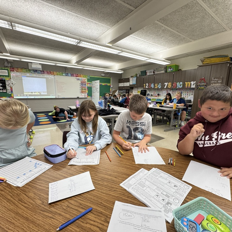 Working with Mrs. Swaid as a team on a multiplication worksheet.