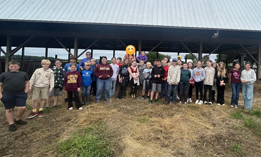 fifth grade class posing in front of cow barn for group photo