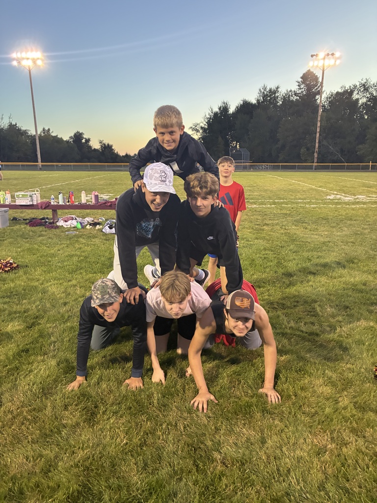 Six boys kneeling on each other to make a pyramid. 