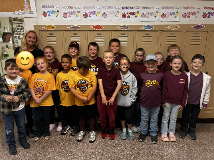 Group of boys and girls posing for a class picture in front of some lockers.  