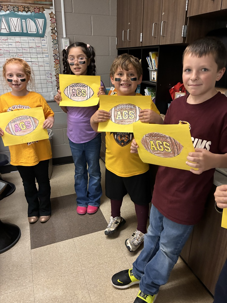 Boys and girls holding a football poster in the classroom. 