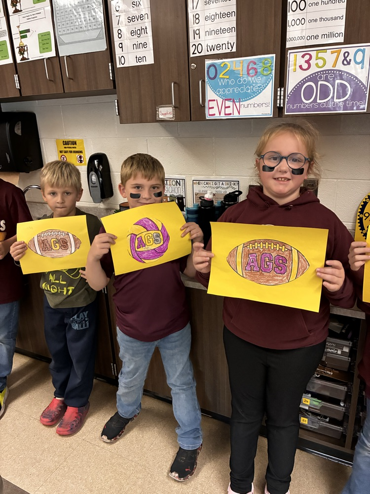 Boys and girls holding a football poster in the classroom. 