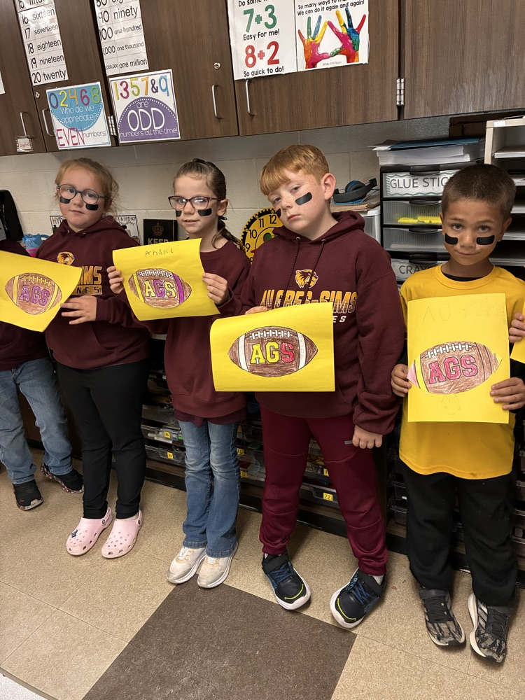 Boys and girls holding a football poster in the classroom. 