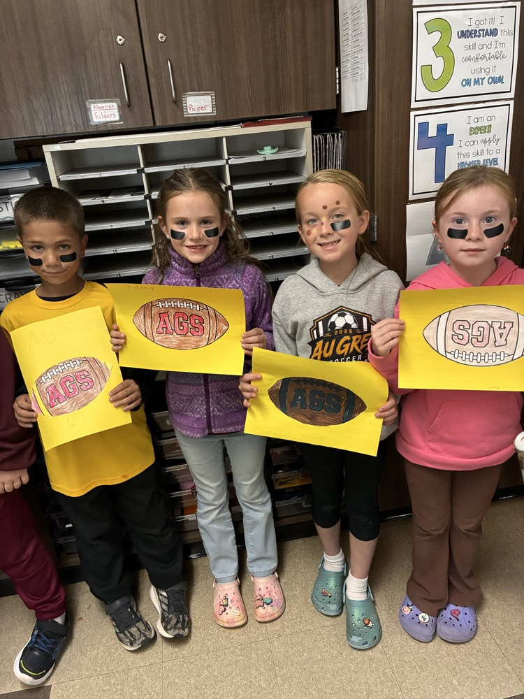 Boys and girls holding a football poster in the classroom. 