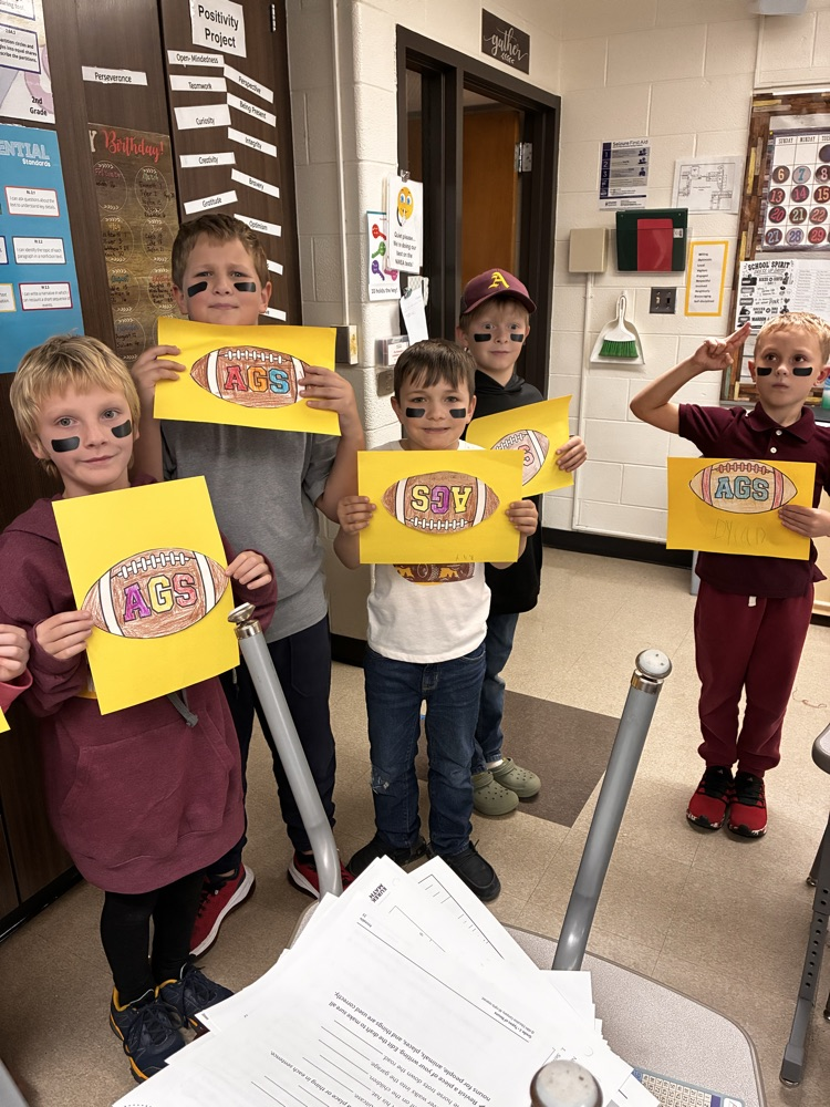 Boys and girls holding a football poster in the classroom. 