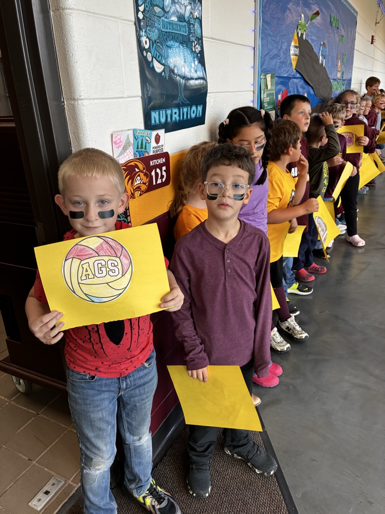 Boys and girls holding a football poster in the hallway. 