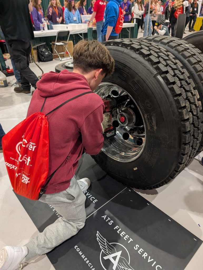 student uses a powertool to tighten lugnots on a tire