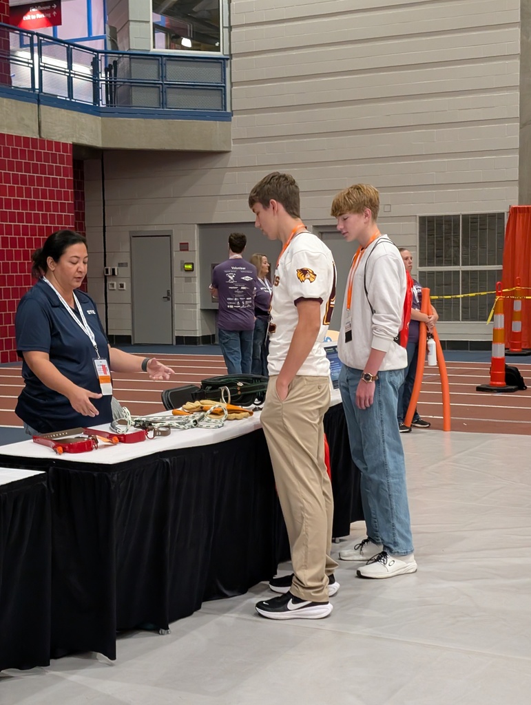 two students talk to a women at a booth at a career fair