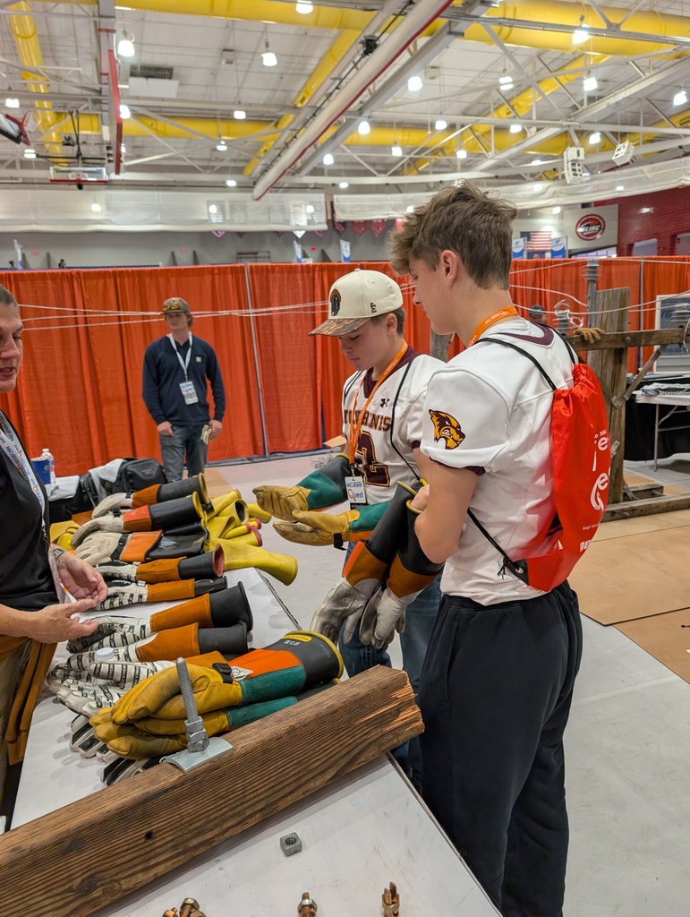 two students put on electrical gloves as they talk to a member of a Lineman union 