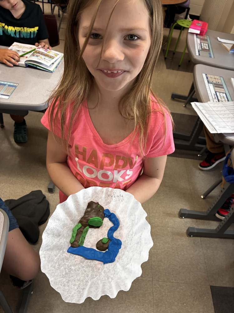 a girl holding clay models of landforms. 