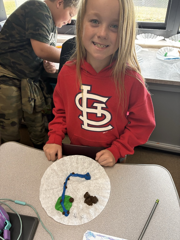 a girl holding clay models of landforms. 