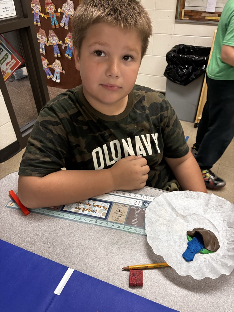a boy holding clay models of landforms. 