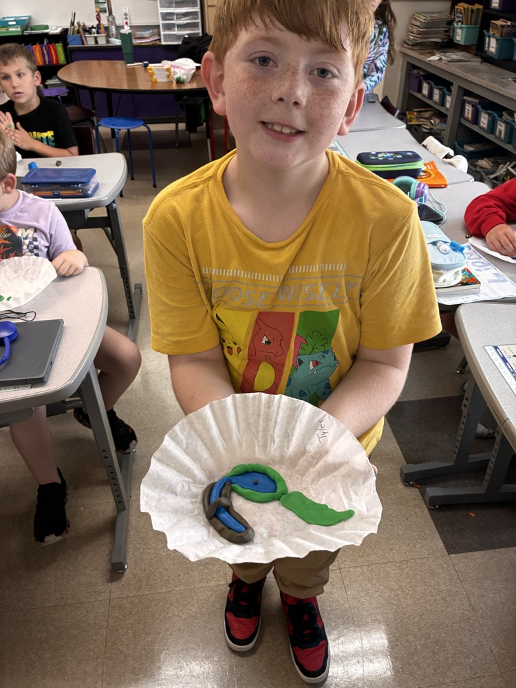 a boy holding clay models of landforms. 