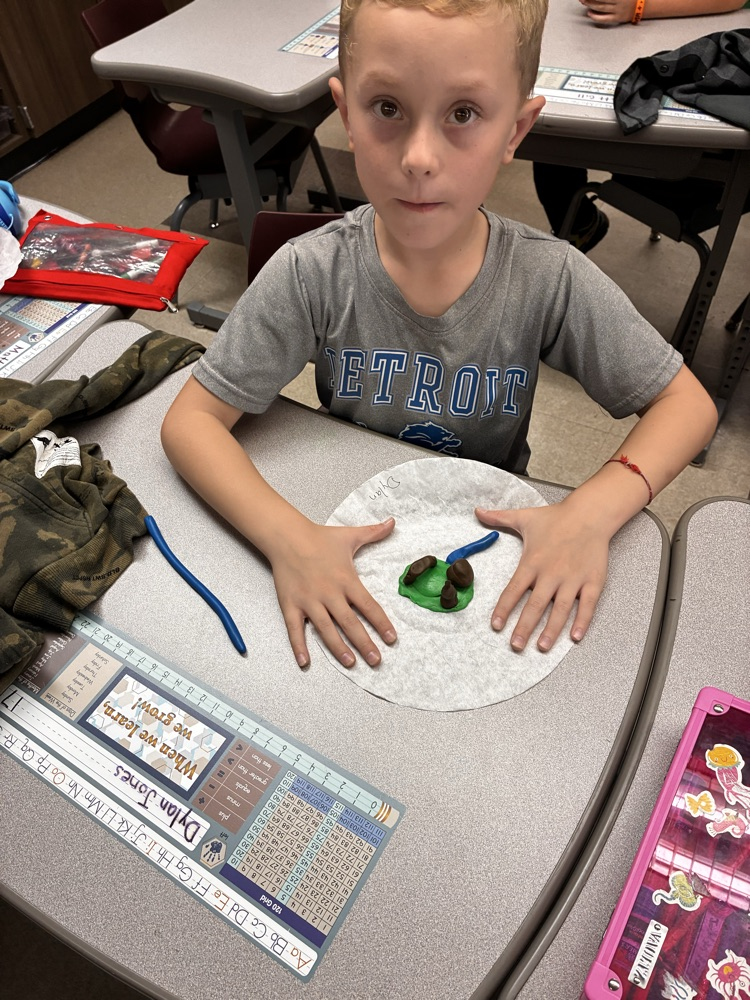 a boy holding clay models of landforms. 