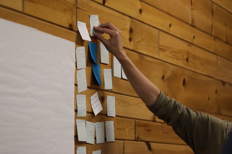 someone putting an idea on the wall on a sticky note
