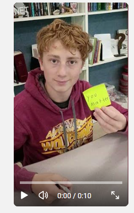student holding up a post-it note