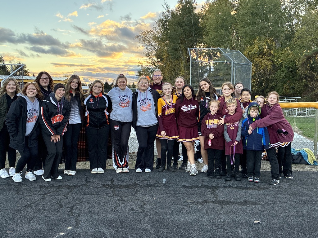 Two groups of cheerleaders standing together with the sun setting in the background