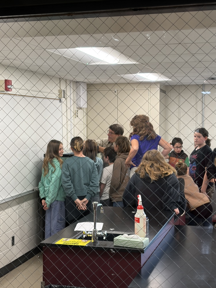 group of students gathered around their instructor and an aquarium