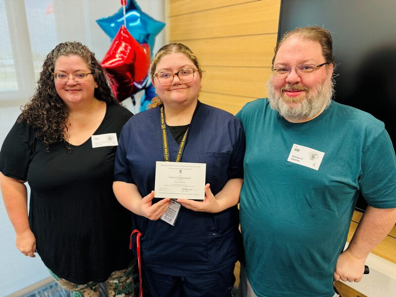 Commended student holding certificate poses with parents