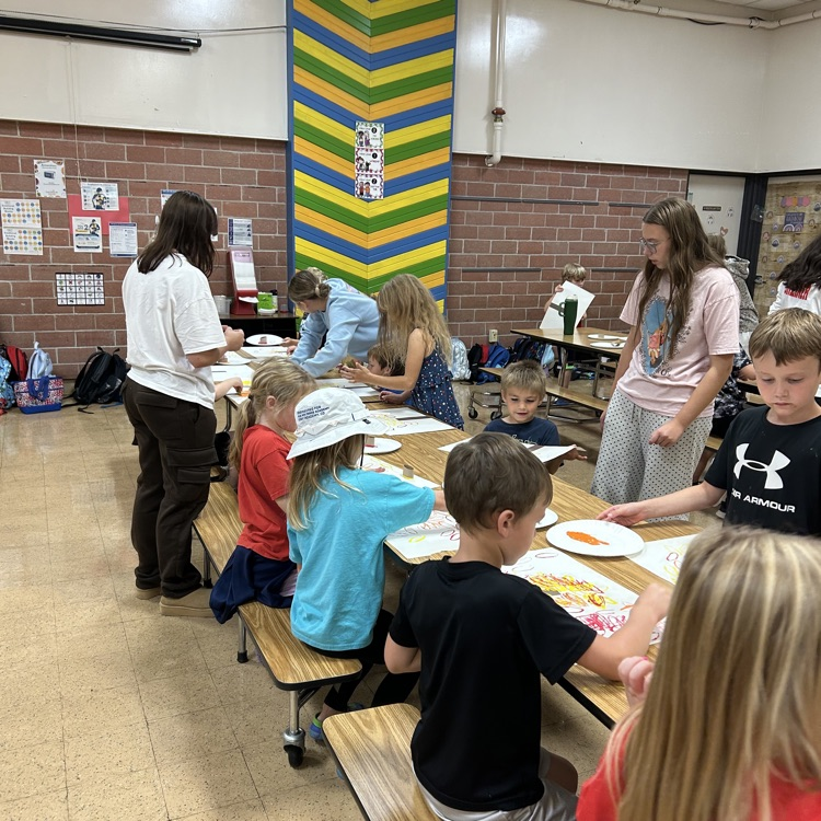 art club member helping younger kids print fall trees