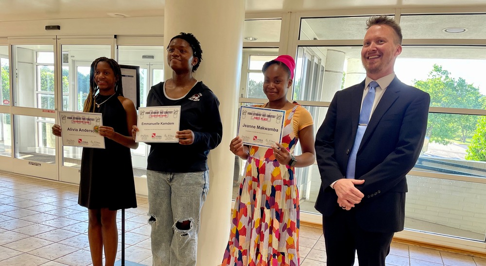 Three students standing with awards, with Steve Cash